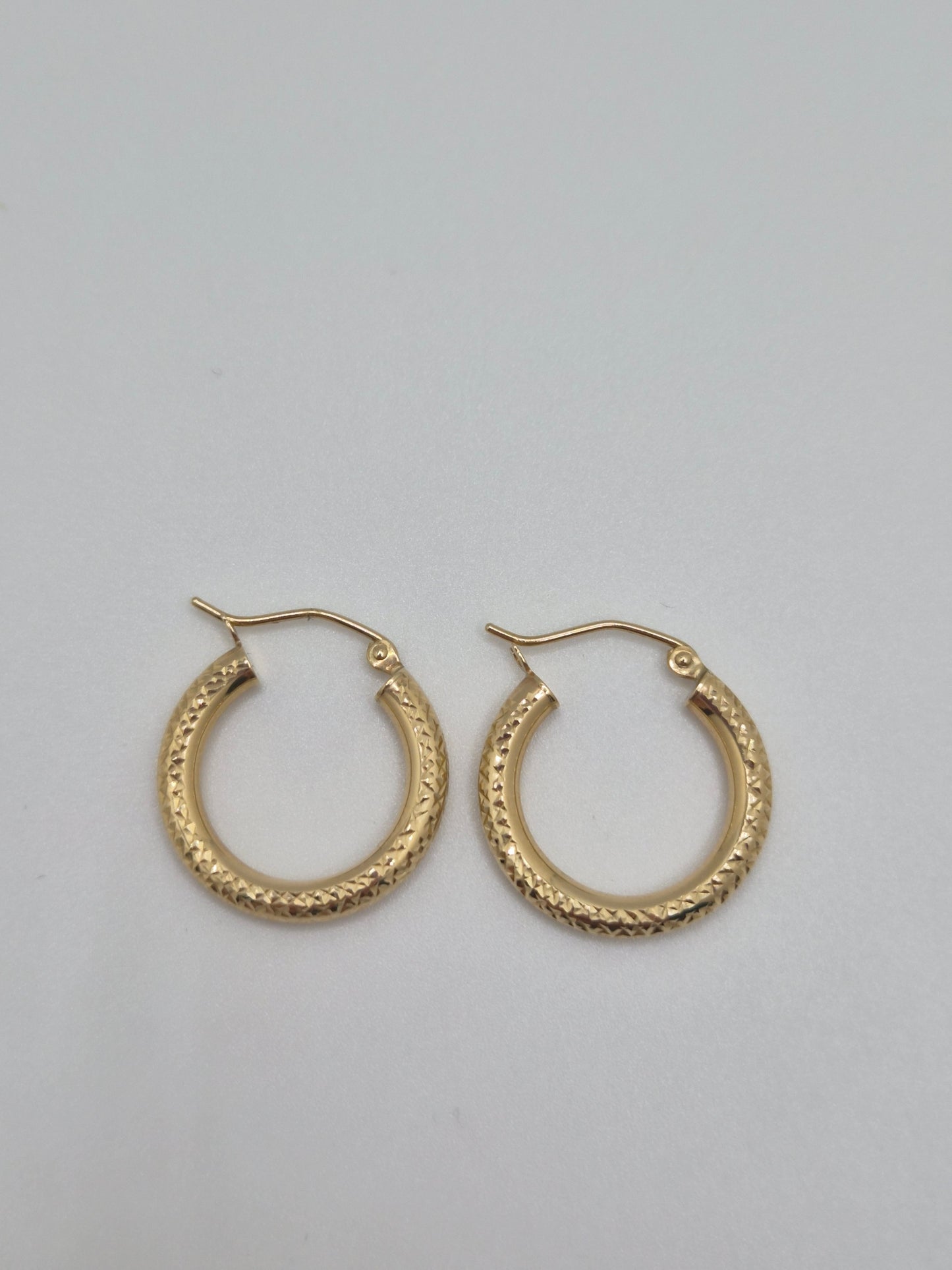 14K yellow gold diamond-cut mini hoop earrings, 20mm round lightweight design with textured shine.