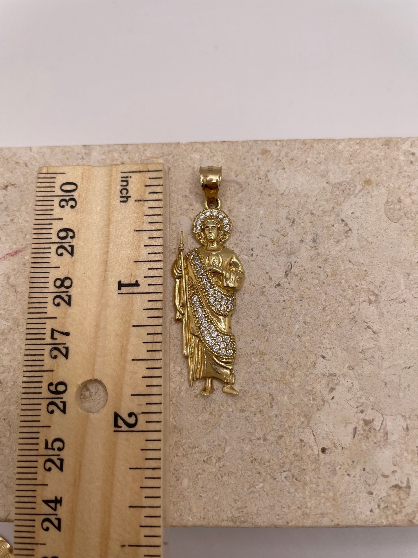 14K yellow gold San Judas pendant with white CZ stones, shown next to a ruler to display dimensions (approximately 1.5 inches)