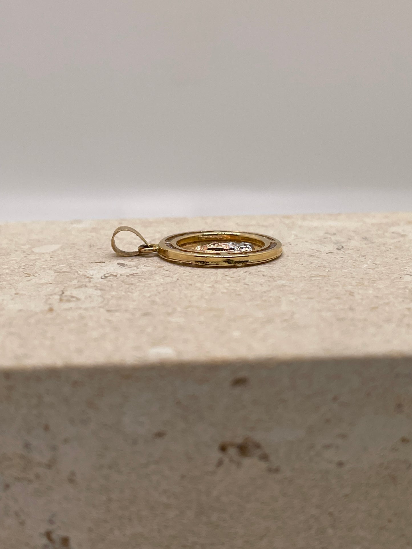 Side view of 14K yellow gold Virgencita pendant showcasing the depth of the design and CZ border