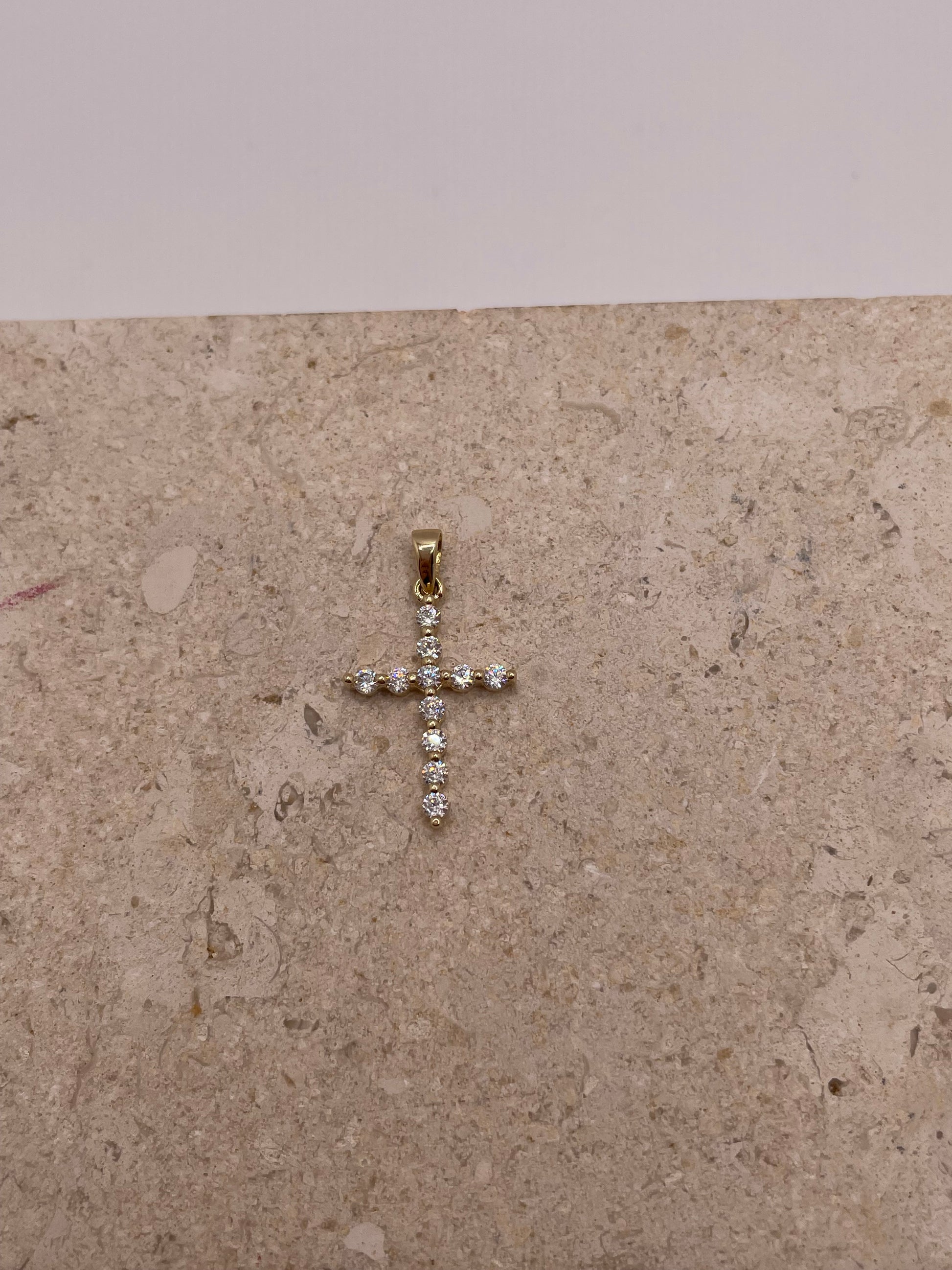 Close-up of 14K yellow gold cross pendant with white CZ stones, showing intricate details and design