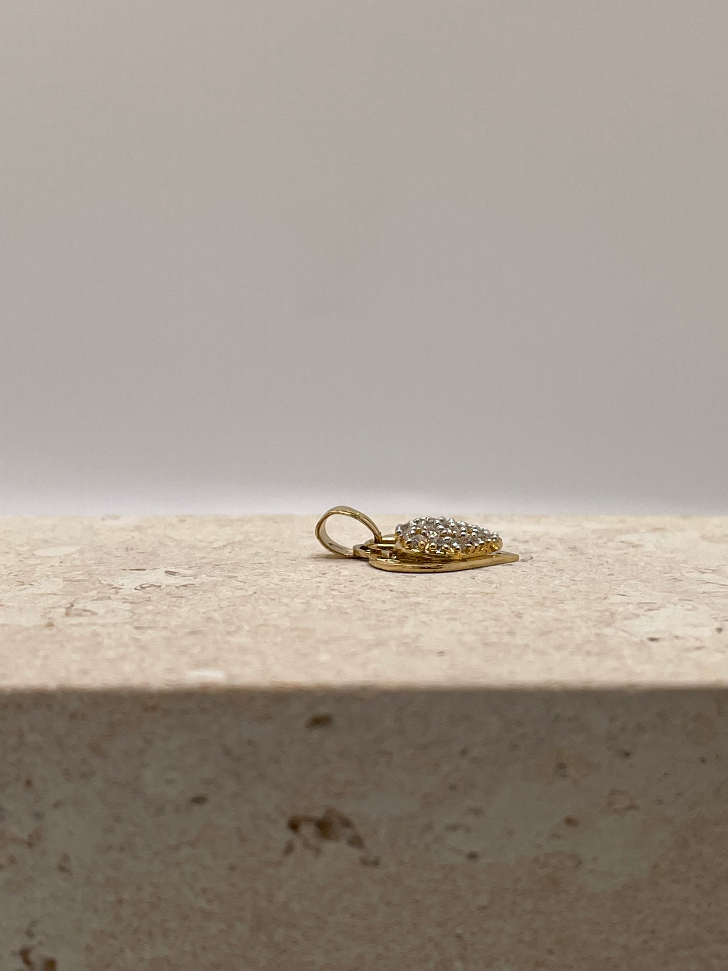 A side view of the pendant showcasing the movement of the top CZ heart, emphasizing the charm's ability to slide to the side. The intricate detail of the pendant's design is highlighted