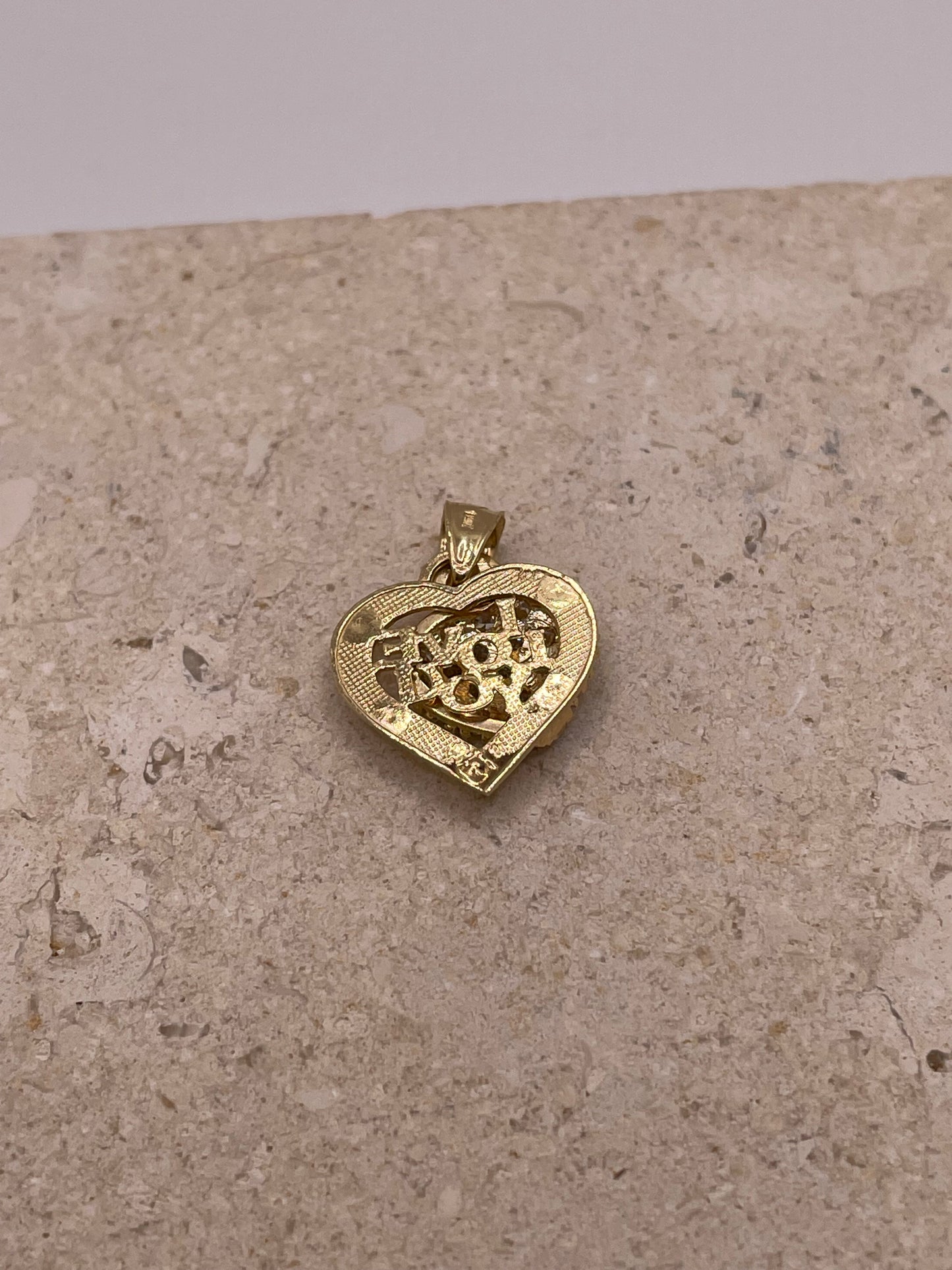 A back view of the pendant showing the smooth, polished surface of the gold heart and the bail, offering a glimpse of how the pendant would hang on a necklace