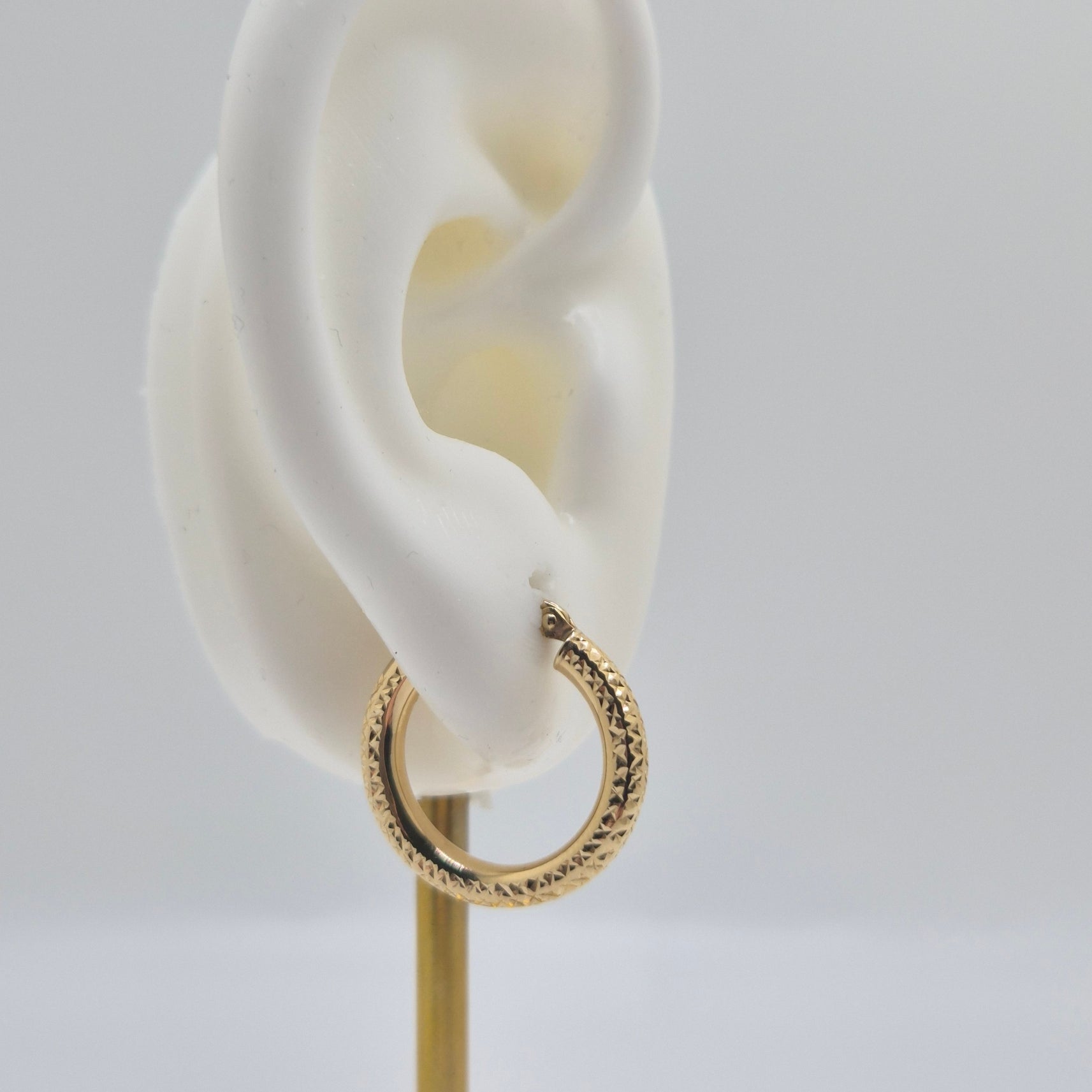 14K yellow gold diamond-cut mini hoop earrings, 20mm round lightweight design with textured shine.