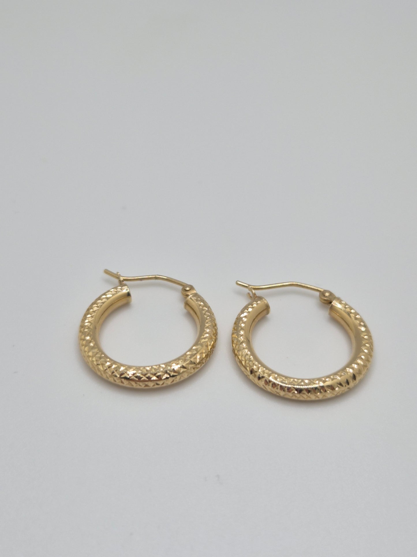 14K yellow gold diamond-cut mini hoop earrings, 20mm round lightweight design with textured shine.