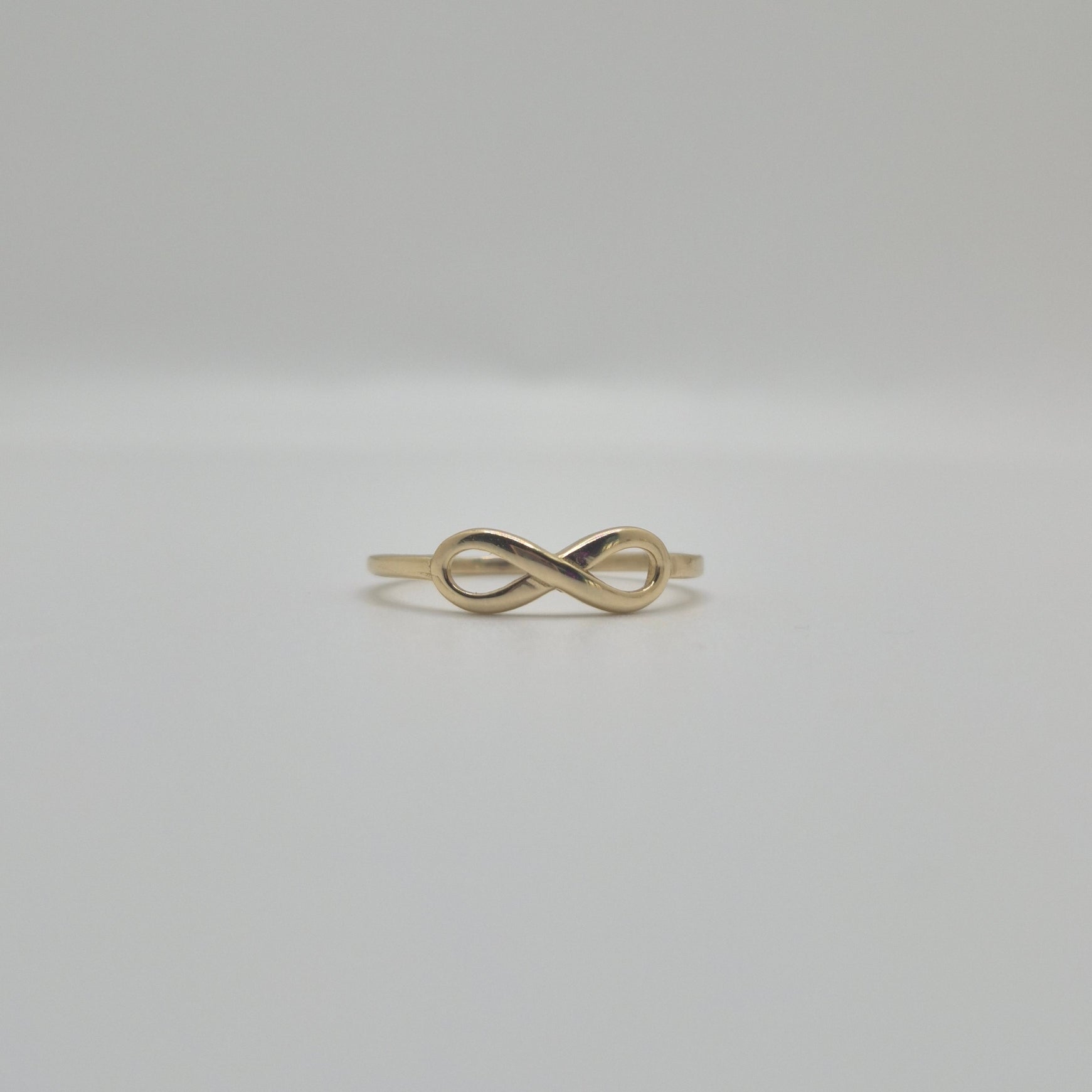 14K yellow gold infinity ring with polished finish, minimal everyday stacking band symbolizing eternal love.