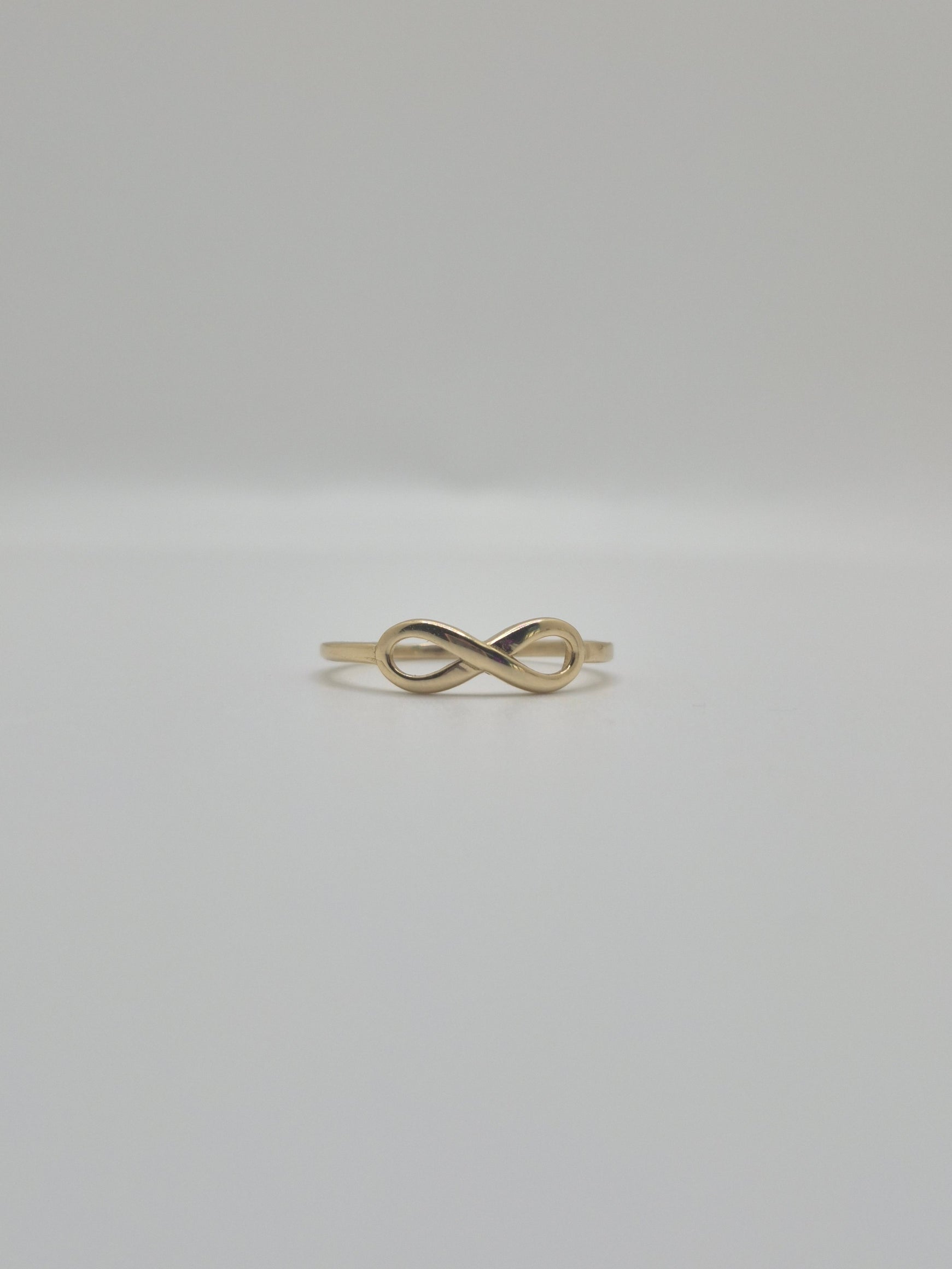 14K yellow gold infinity ring with polished finish, minimal everyday stacking band symbolizing eternal love.