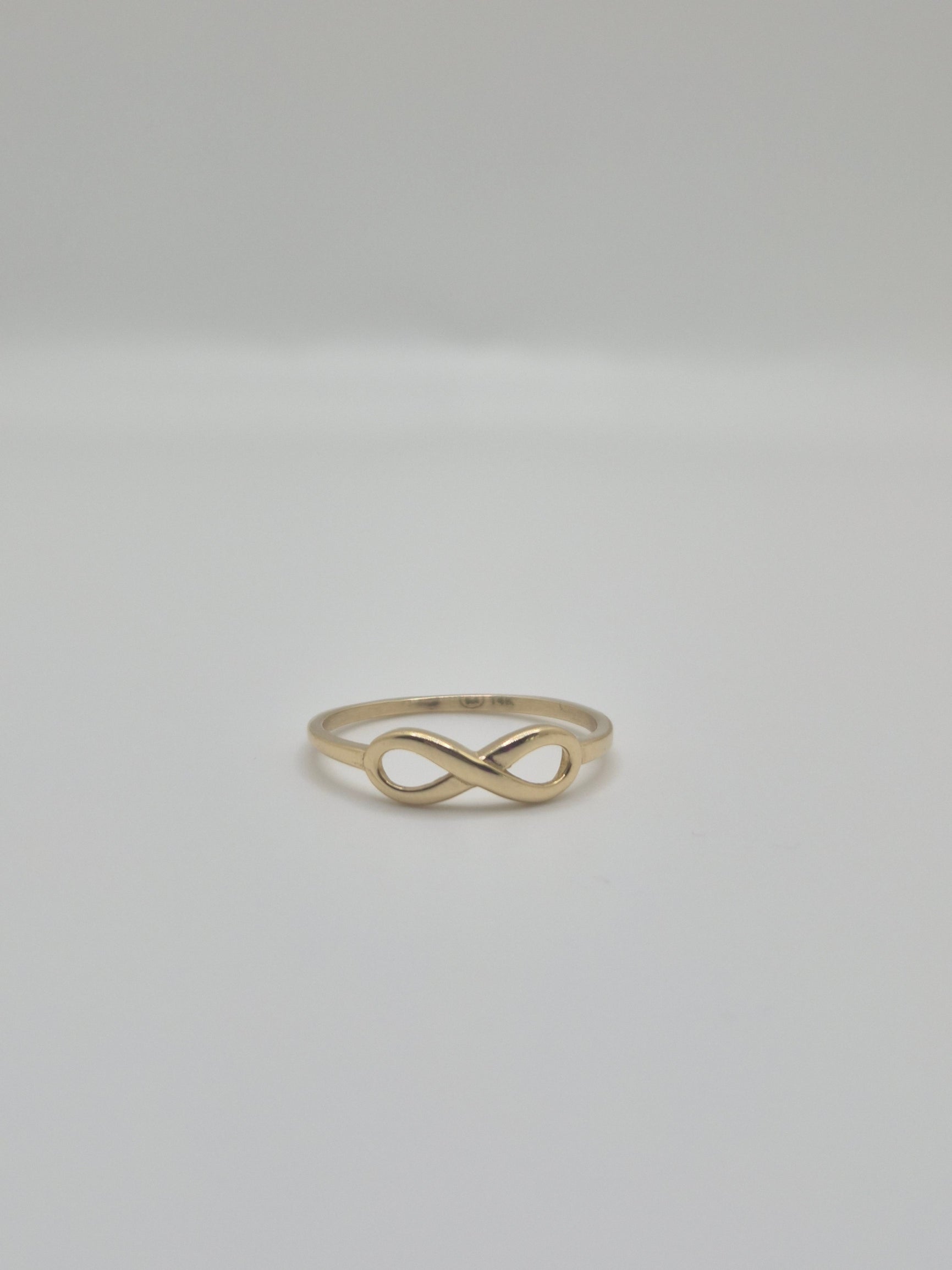 14K yellow gold infinity ring with polished finish, minimal everyday stacking band symbolizing eternal love.