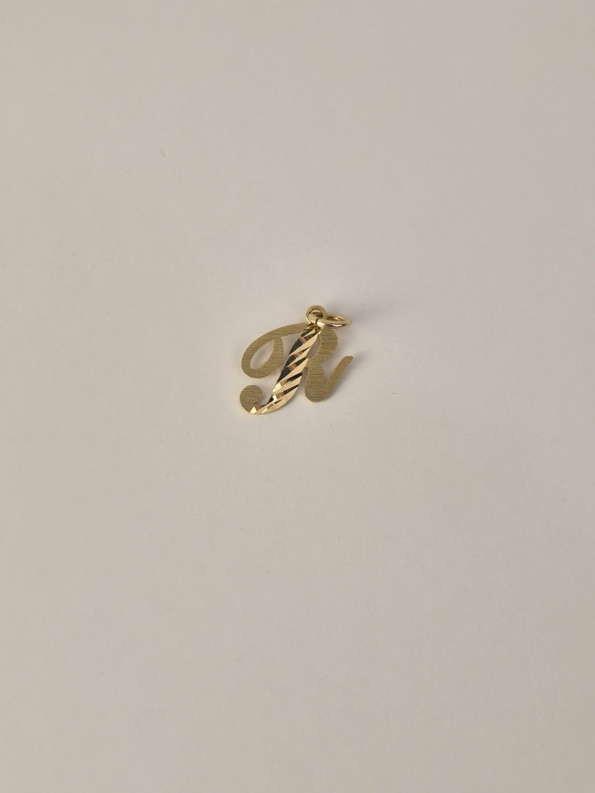 Colgante con inicial pequeña en cursiva con corte de diamante en oro de 14 quilates