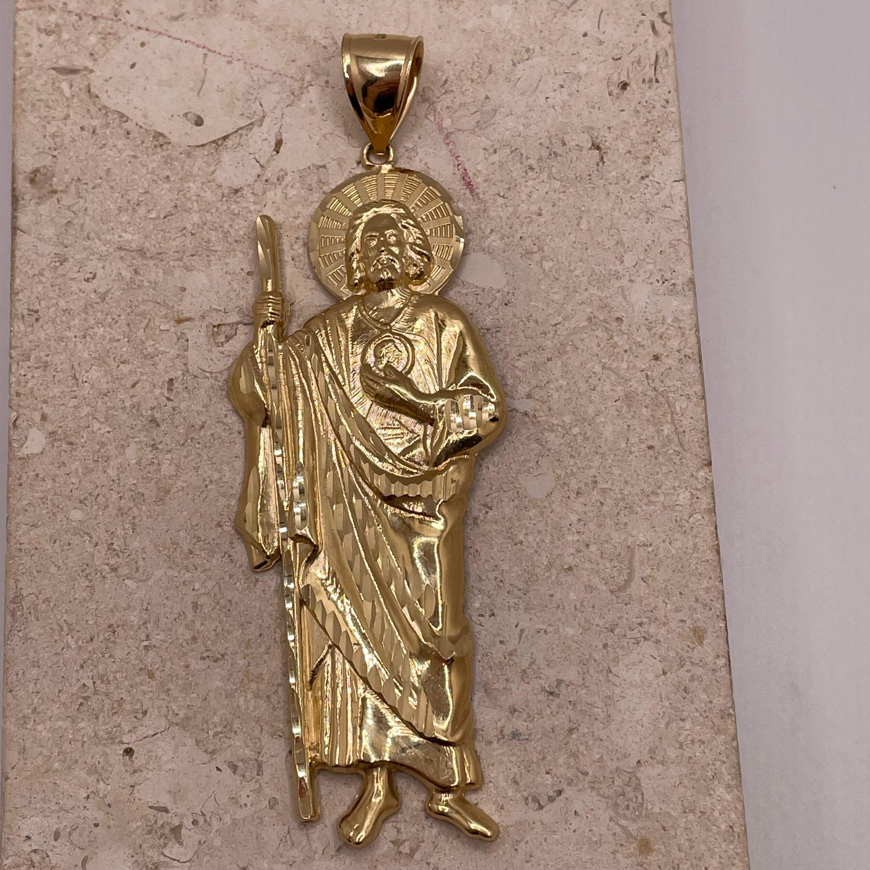 Close-up of 14K yellow gold large San Judas pendant with detailed craftsmanship and gold finish