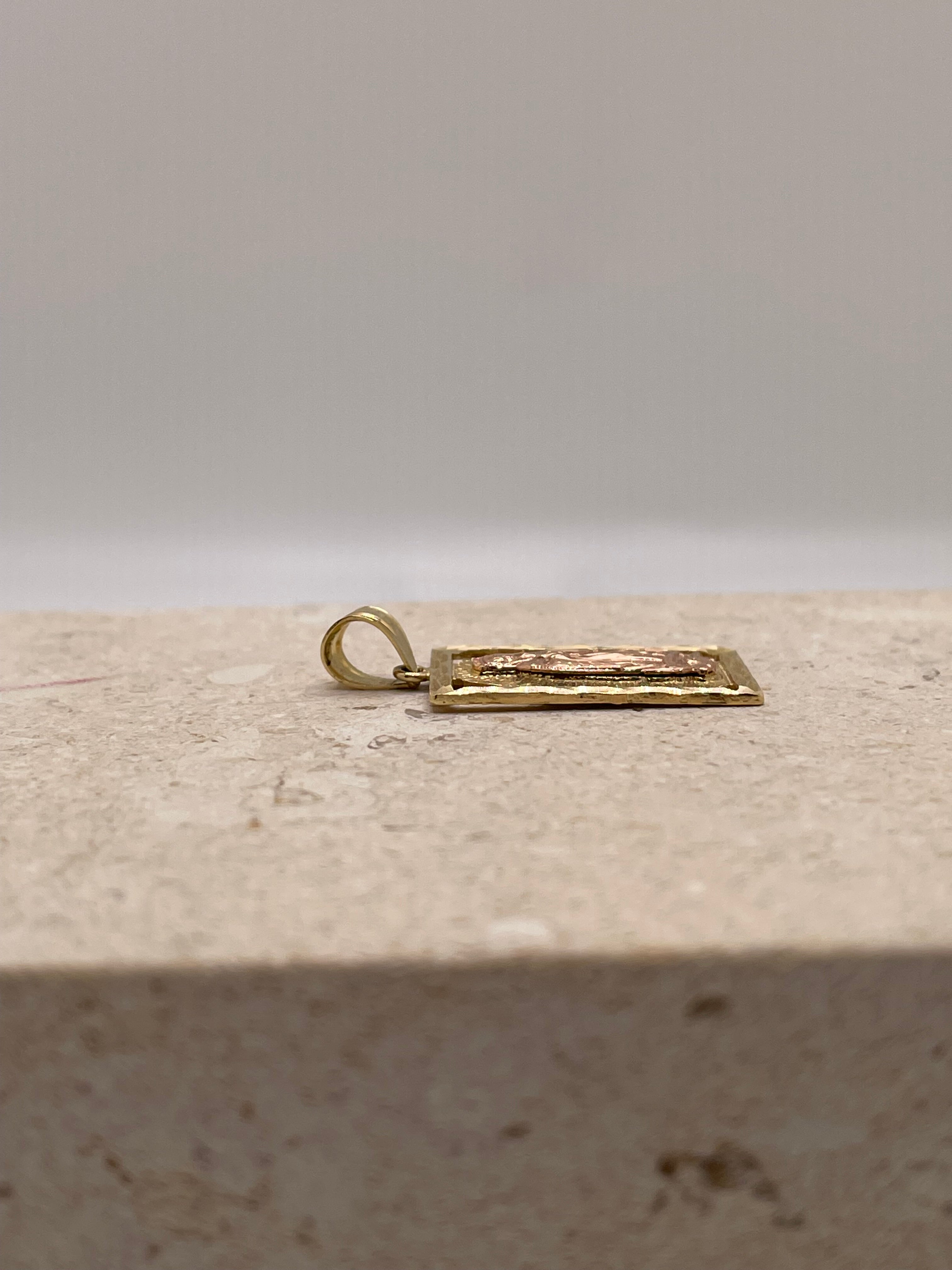 Side view of 14K gold vertical Virgen Mary pendant showing the depth of the design and diamond-cut border