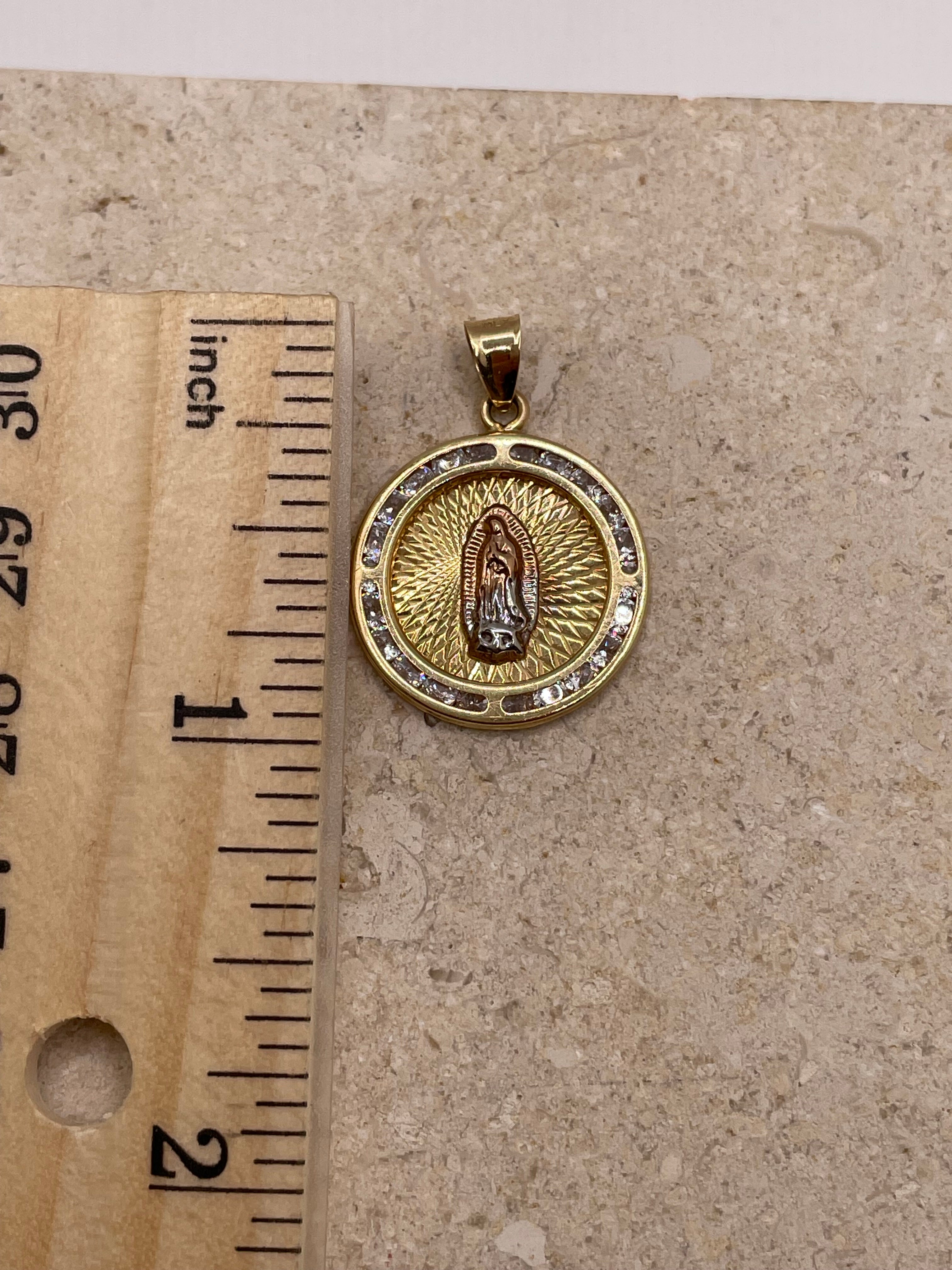 14K yellow gold Virgencita pendant with CZ border, shown next to a ruler to display dimensions (approximately 1 inch, including the bail)