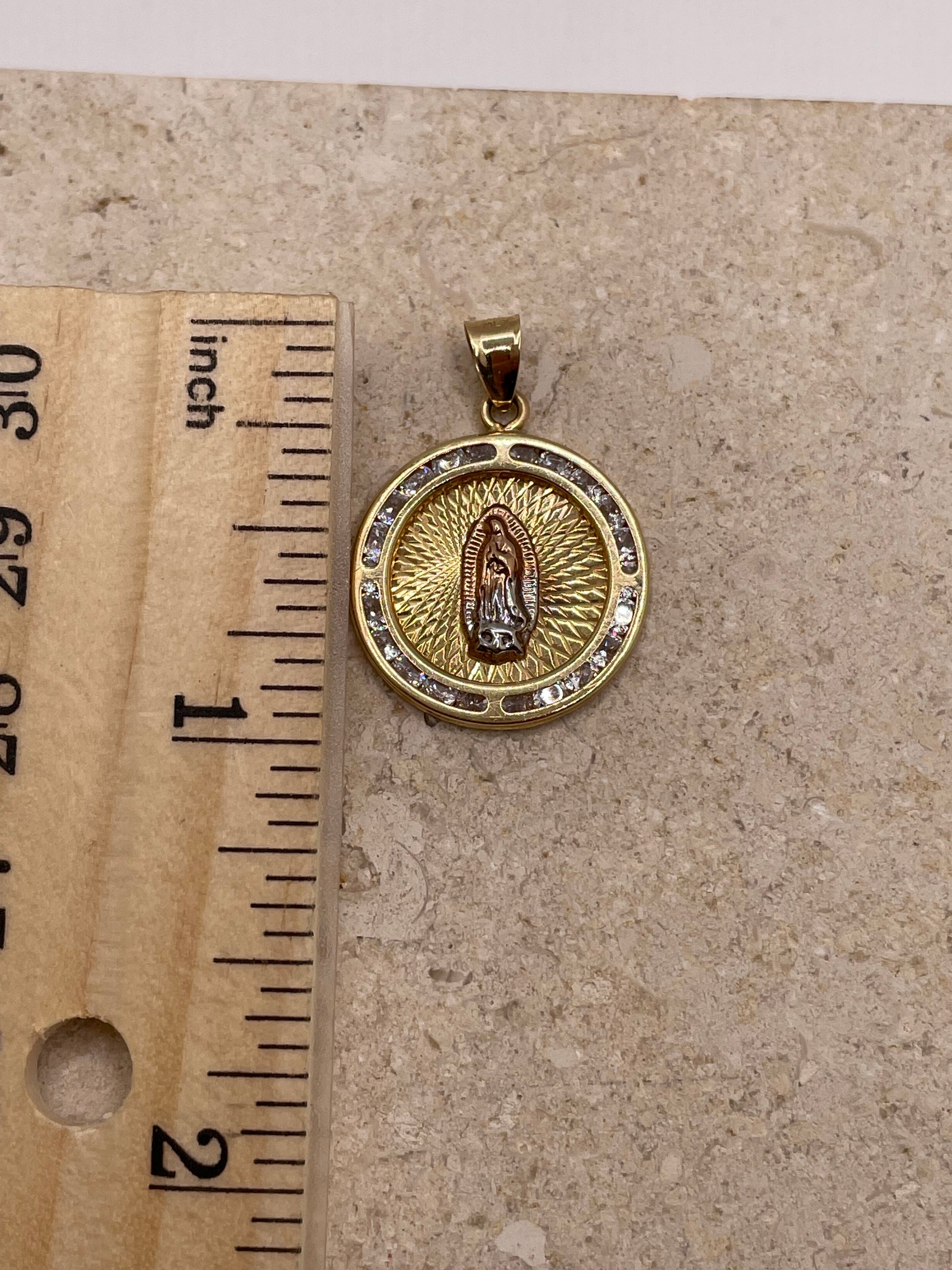 14K yellow gold Virgencita pendant with CZ border, shown next to a ruler to display dimensions (approximately 1 inch, including the bail)