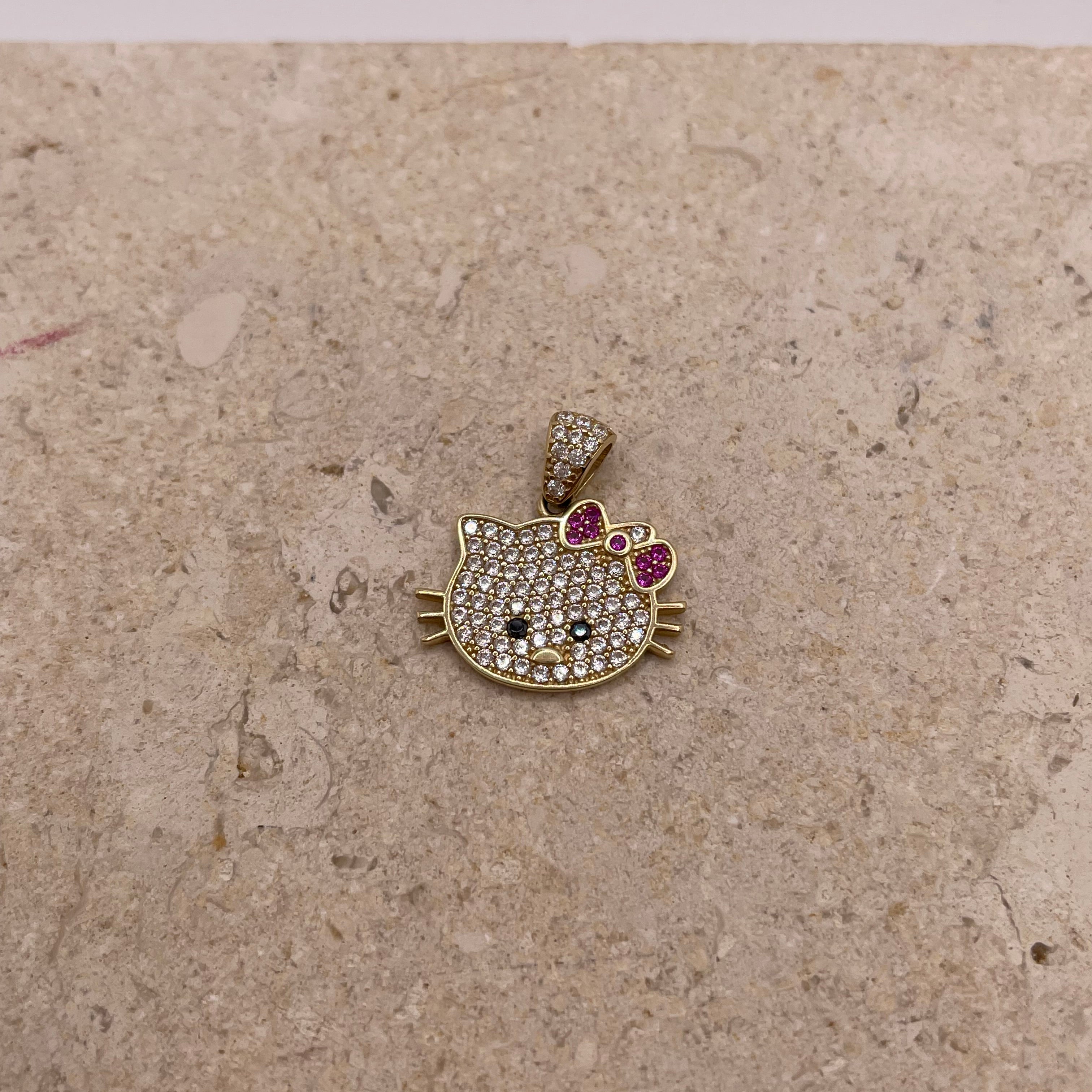Close-up of 14K gold Hello Kitty pendant with white CZ stones, black CZ eyes and nose, and a pink CZ bow