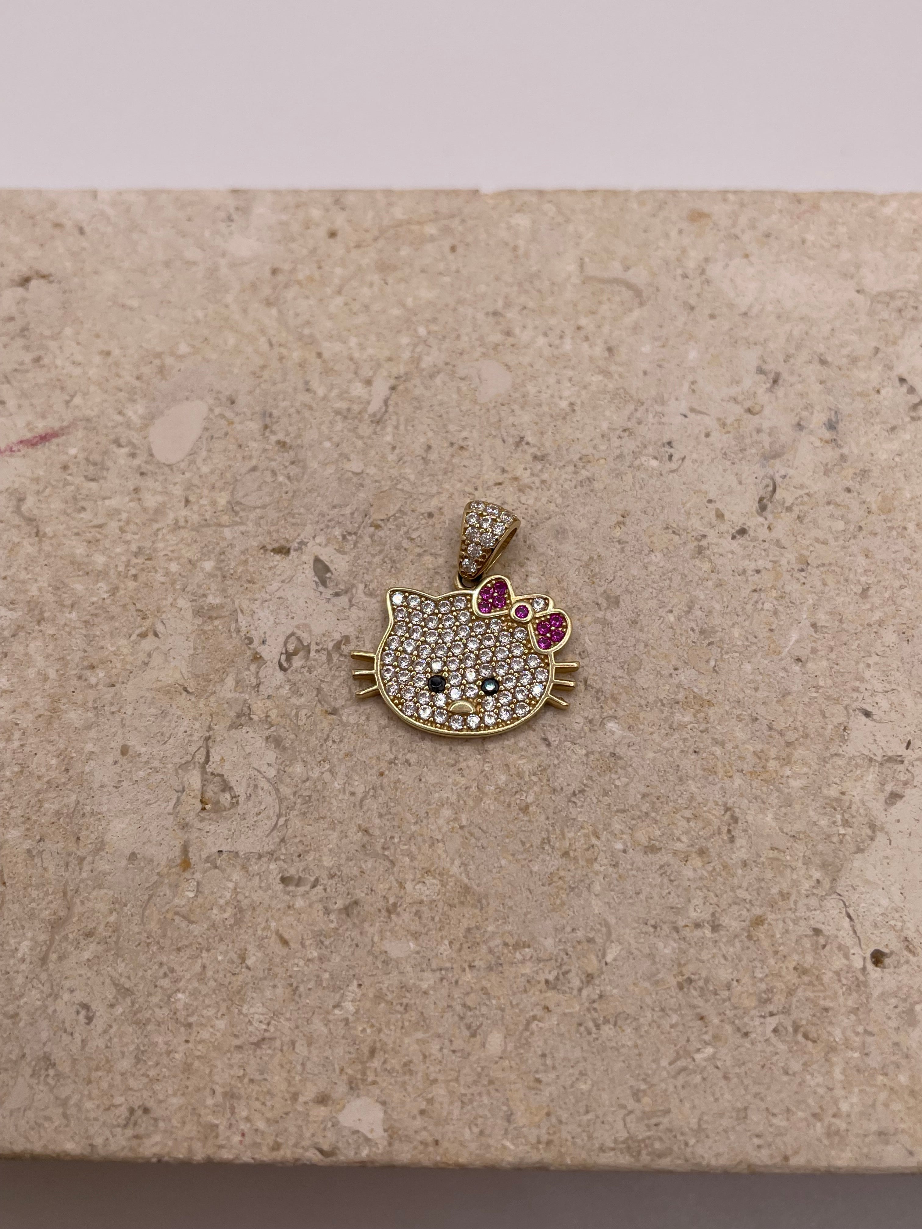 Close-up of 14K gold Hello Kitty pendant with white CZ stones, black CZ eyes and nose, and a pink CZ bow