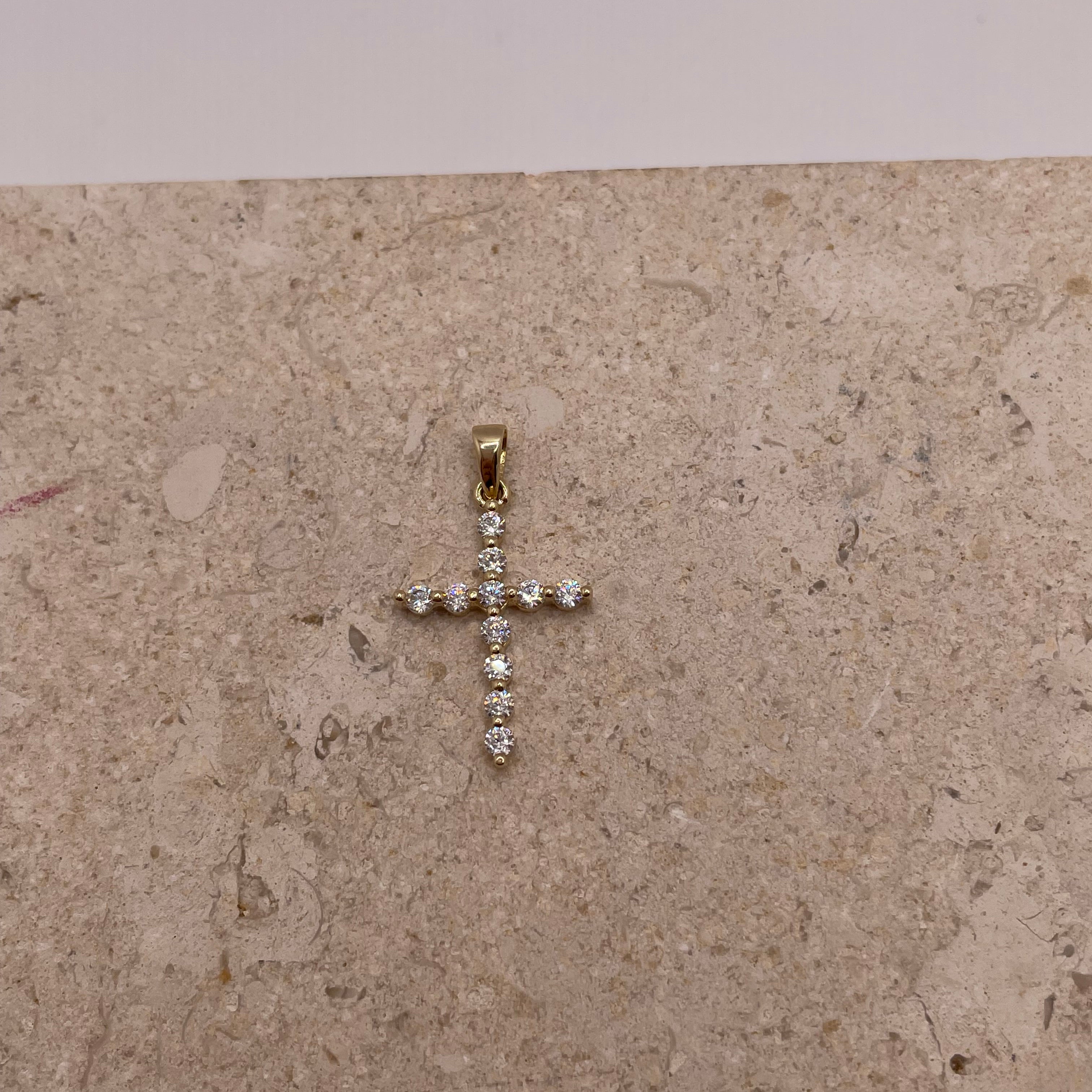 Close-up of 14K yellow gold cross pendant with white CZ stones, showing intricate details and design