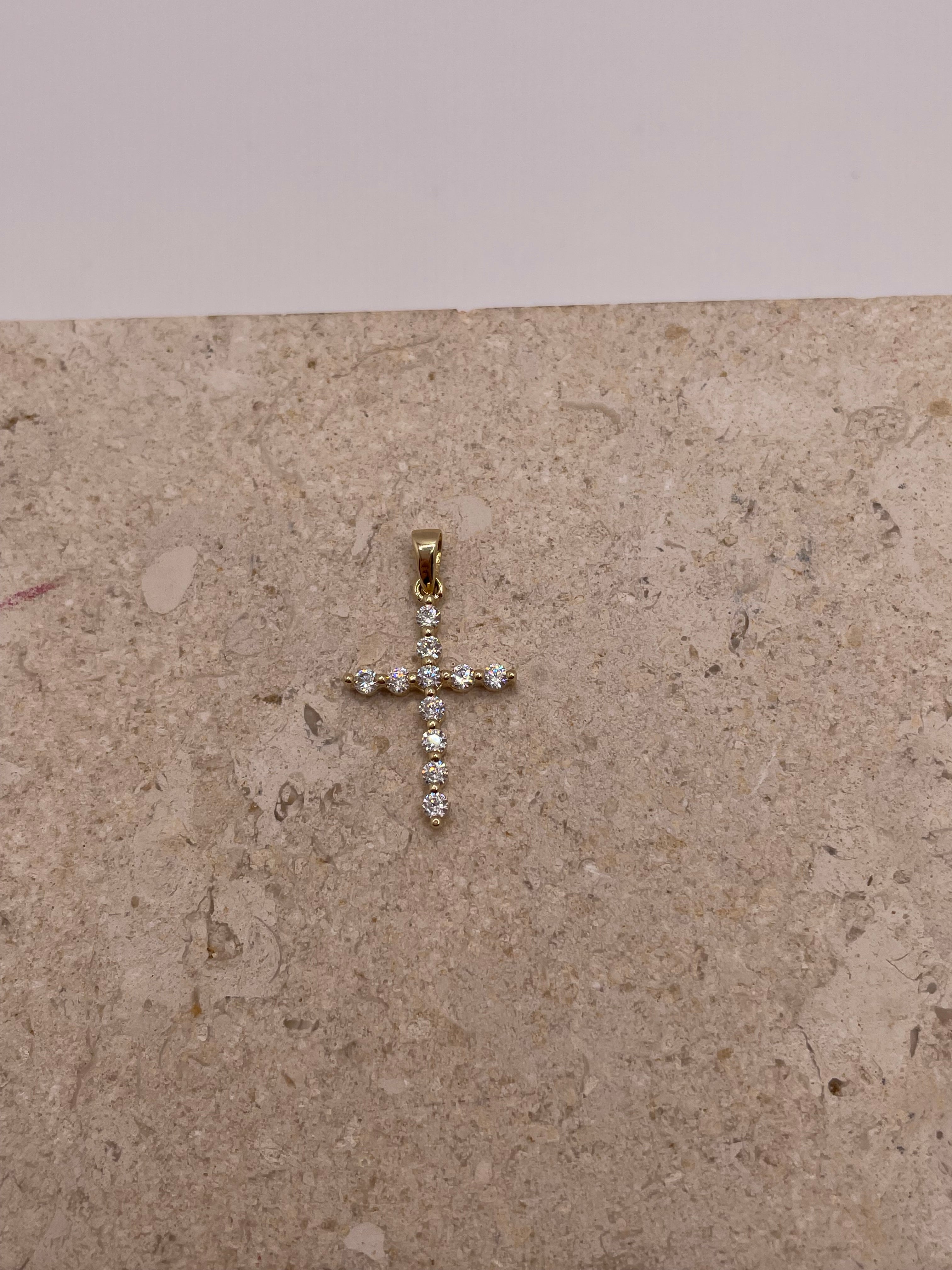 Close-up of 14K yellow gold cross pendant with white CZ stones, showing intricate details and design