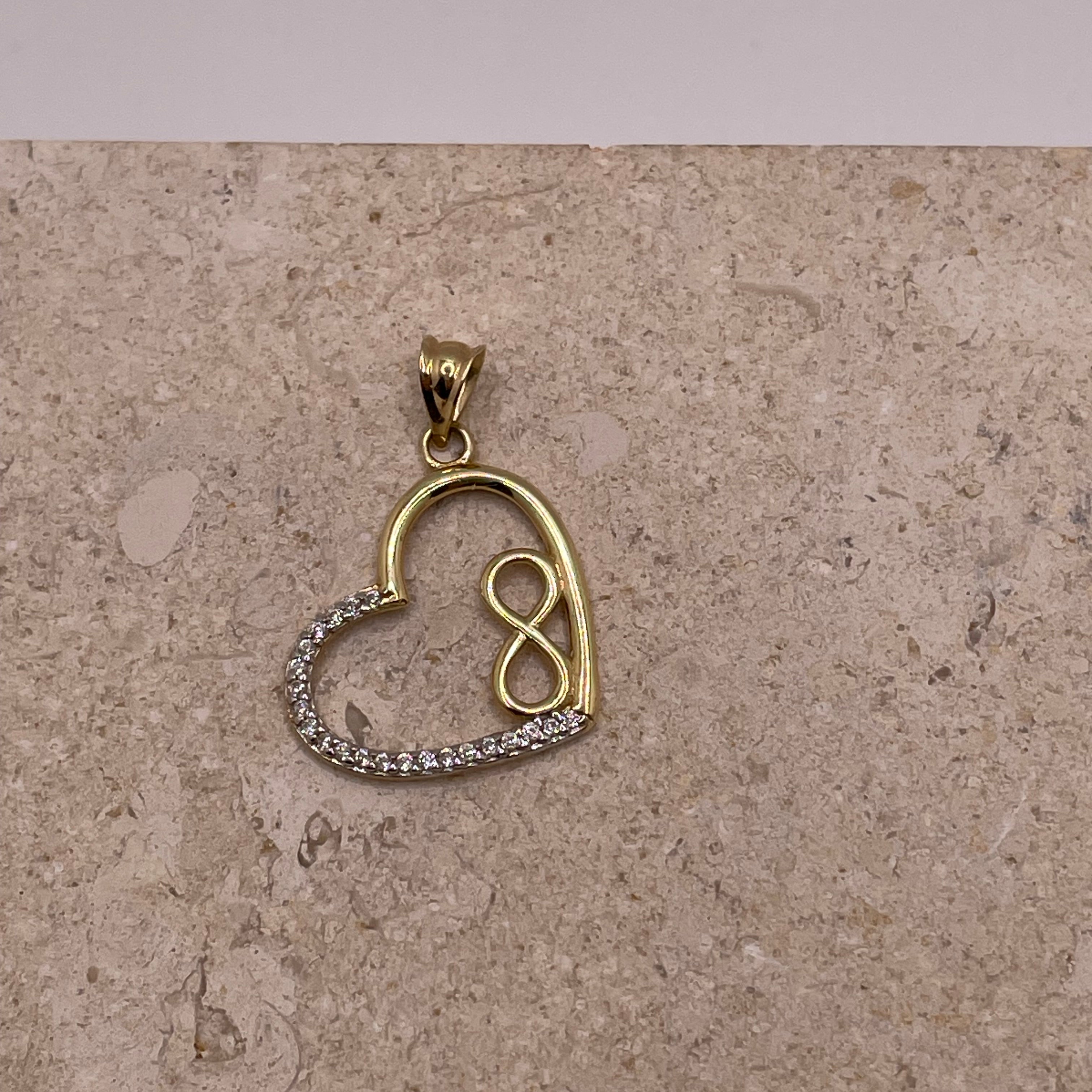 Close-up of 14K gold open heart pendant with small gold infinity symbol and white CZ stones on the left