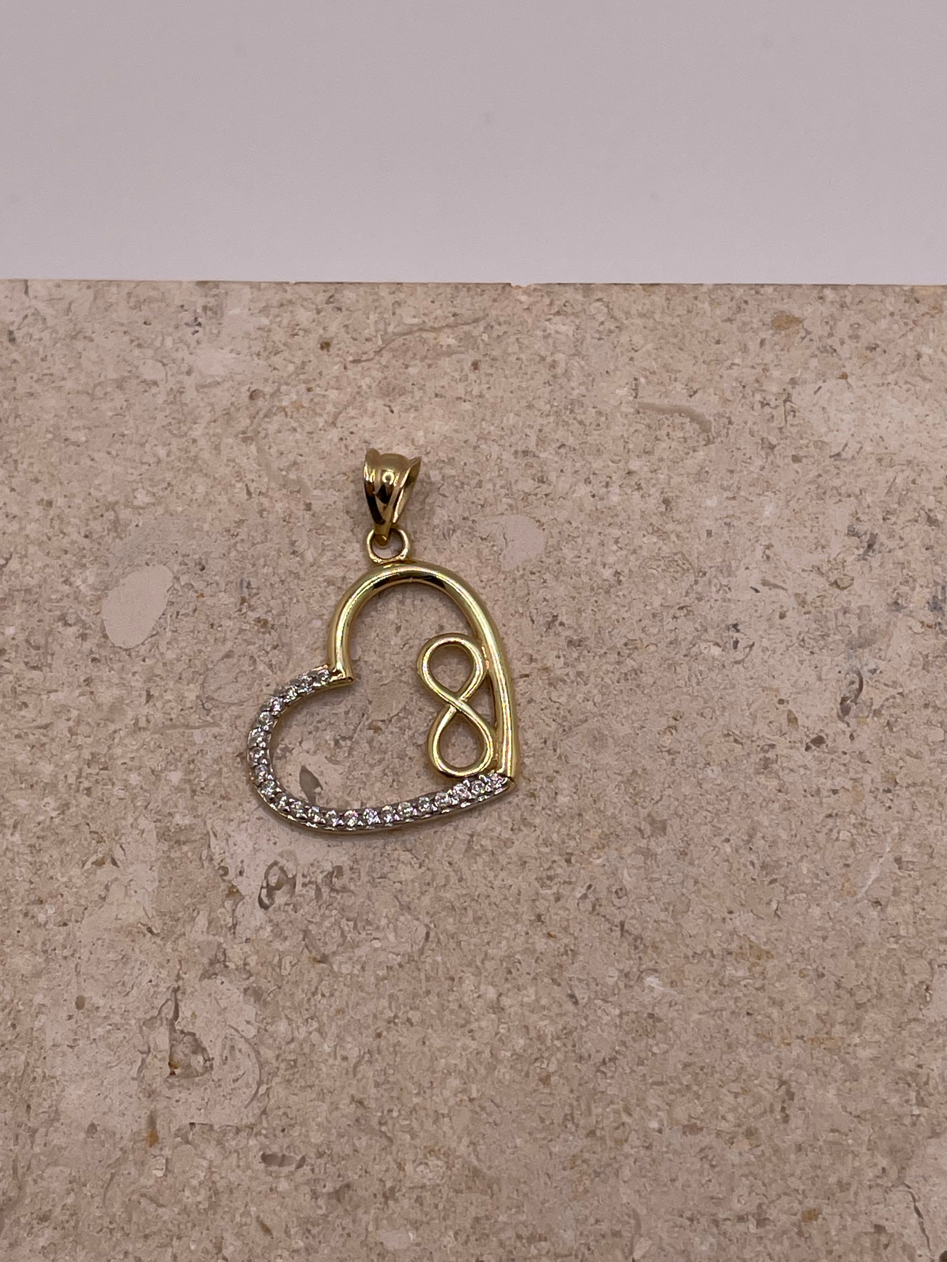 Close-up of 14K gold open heart pendant with small gold infinity symbol and white CZ stones on the left