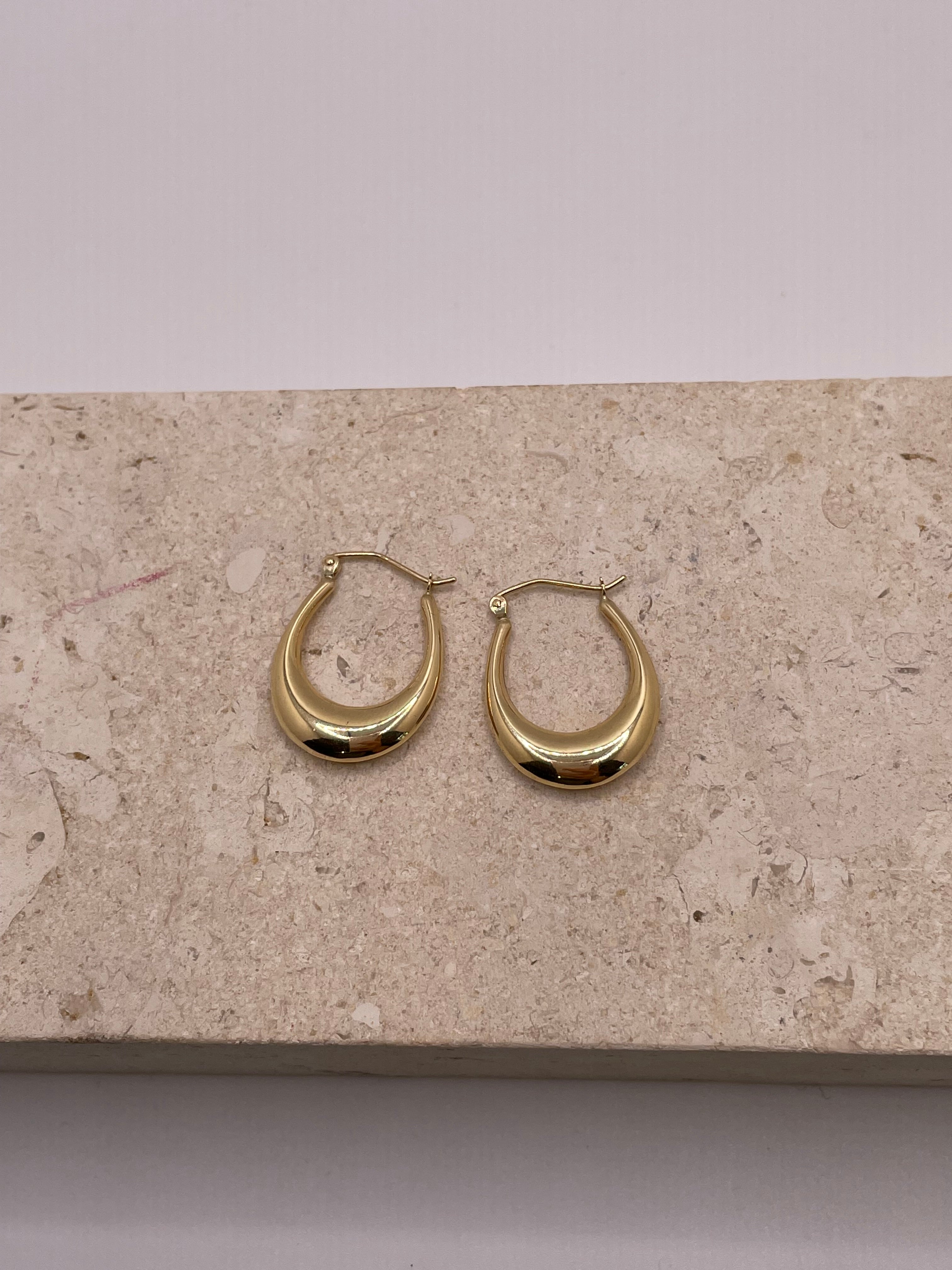 A close-up image showing the 14k gold polished hollow hoop earrings, highlighting their sleek and shiny surface. The hollow construction adds a light, airy feel to the design